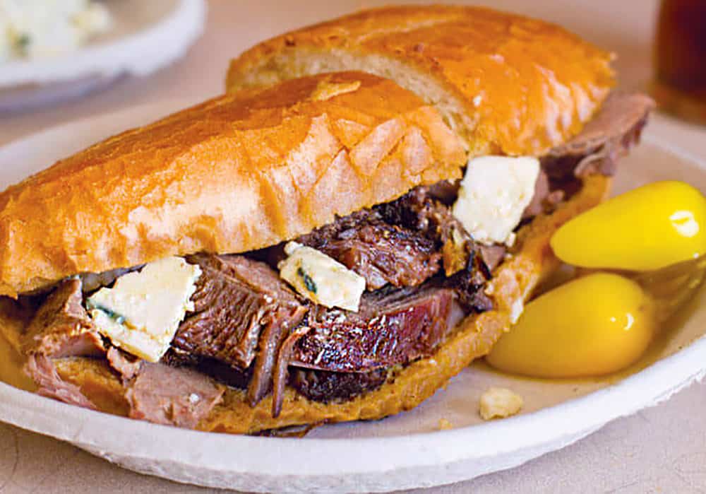 A french dipped sandwich of hand-carved slow-roasted leg of lamb with chunks of goat cheese on a fresh house-baked French roll... yum!