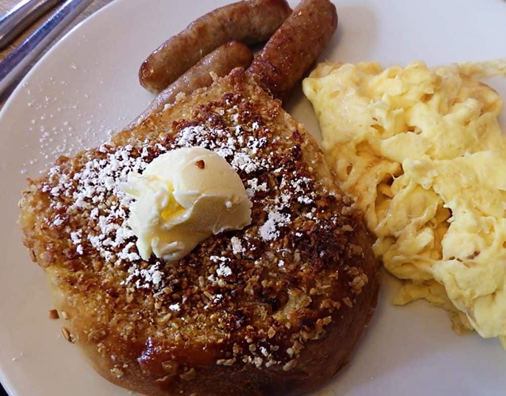 Granola-coated thick French toast, topped with a huge ball of butter, with sausage links and scrambled eggs.