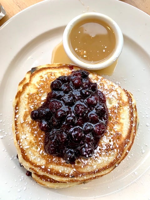 A stack of signature pancakes with a scoop of stewed wild Maine blueberry compote.