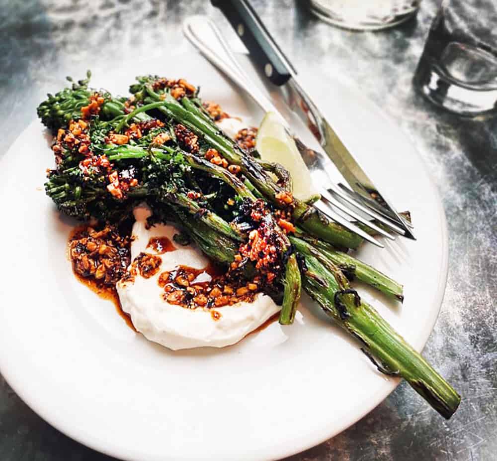 A plate of grilled broccolini with salsa macha, crema and lime at Tasty and Alder in Portland, Oregon