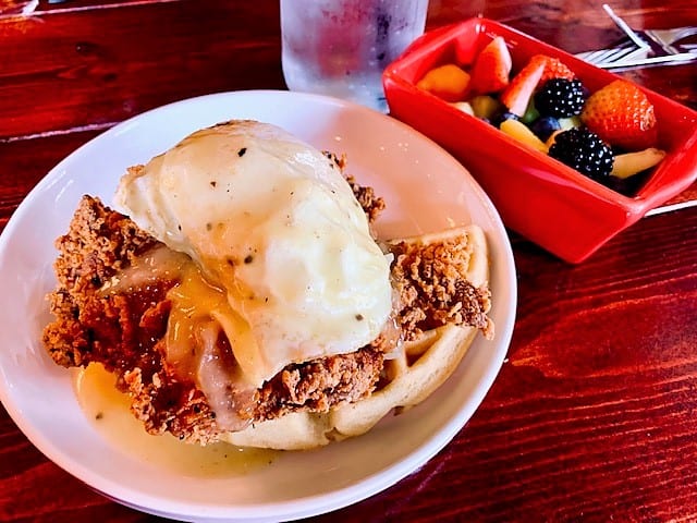 Waffle topped with crispy fried chicken and a perfectly fried egg then topped with savory chicken gravy