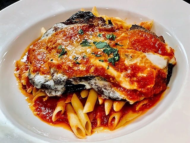 Slices of fried eggplant top pasta and are then smothered with cheese and sauce.