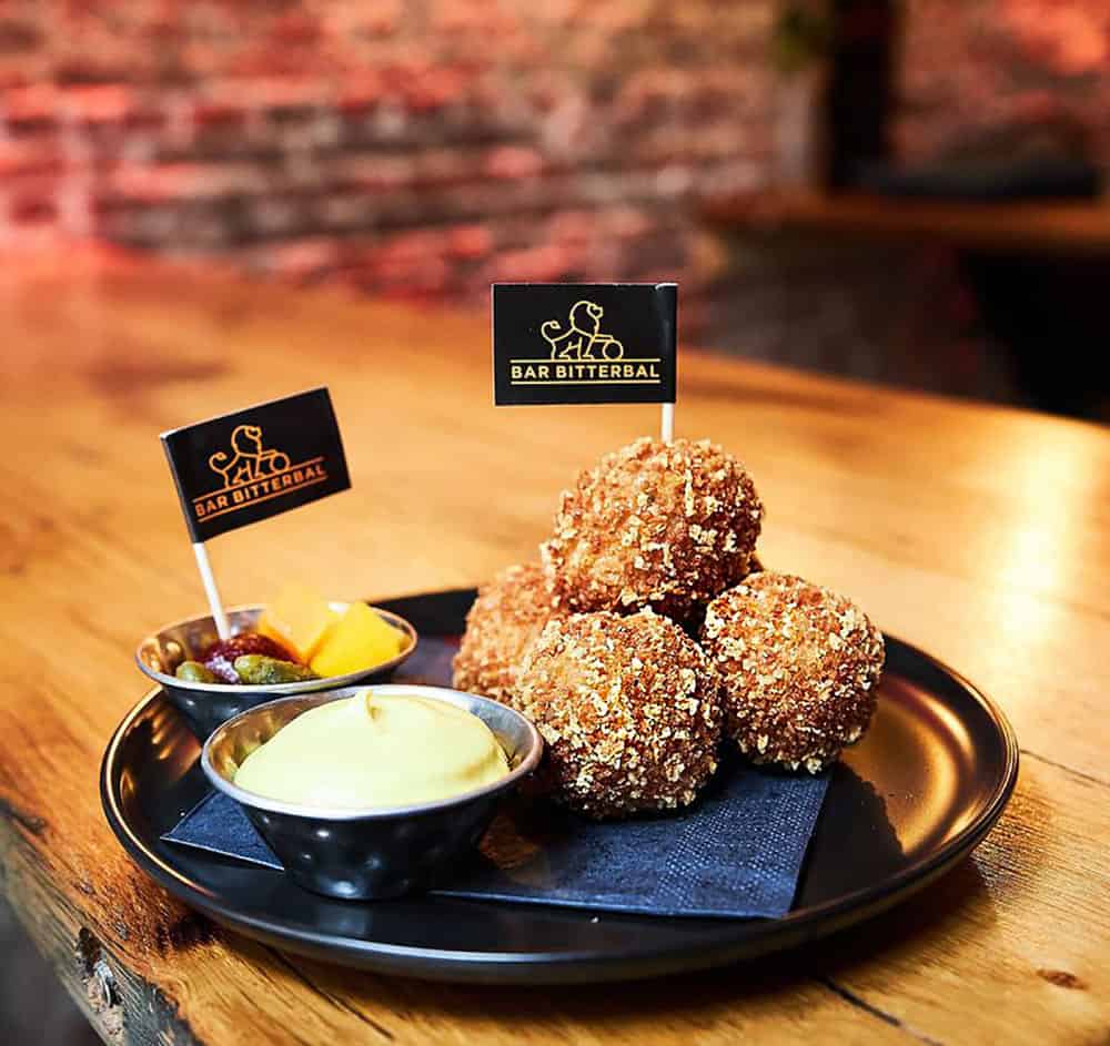 A pile of deep-friend and golden veal bitterballen with dipping sauce and a dish of gherkins at Barb Bitterbal in Amsterdam, where you can sample the largest variety of these popular Dutch bar snacks in the world.